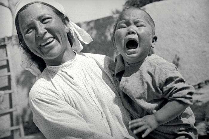 Женщина держащая плачущего ребенка на руках. Фото: Max Penson.