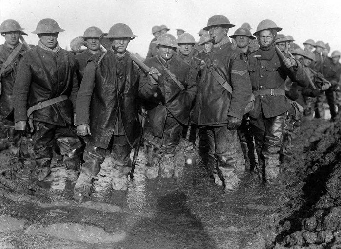 Британские солдаты стоят по колено в грязи на французских позициях.