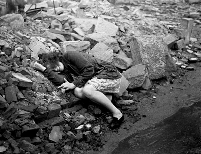 Плачущая над развалинами своего дома женщина. 