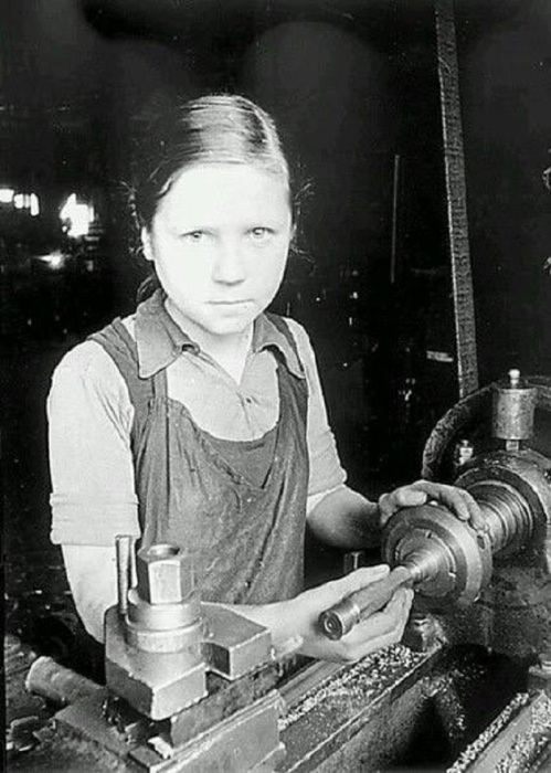 Девочка работает за токарным станком. СССР, Ленинград, 1943 год.