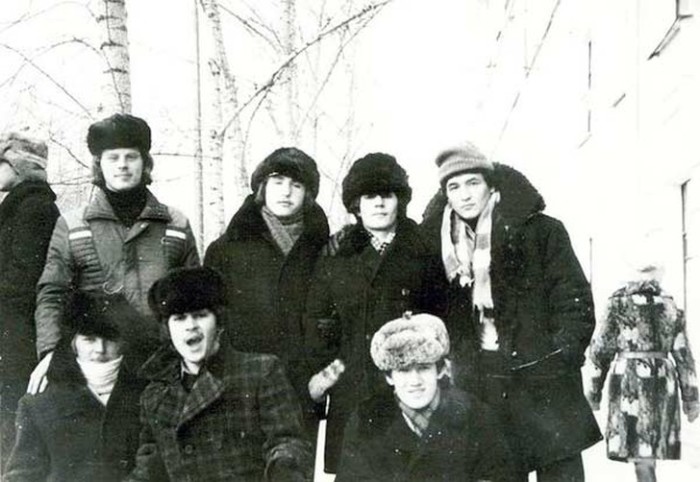 Юноши в зимних куртках с воротниками из искусственного меха и шапками-ушанками.