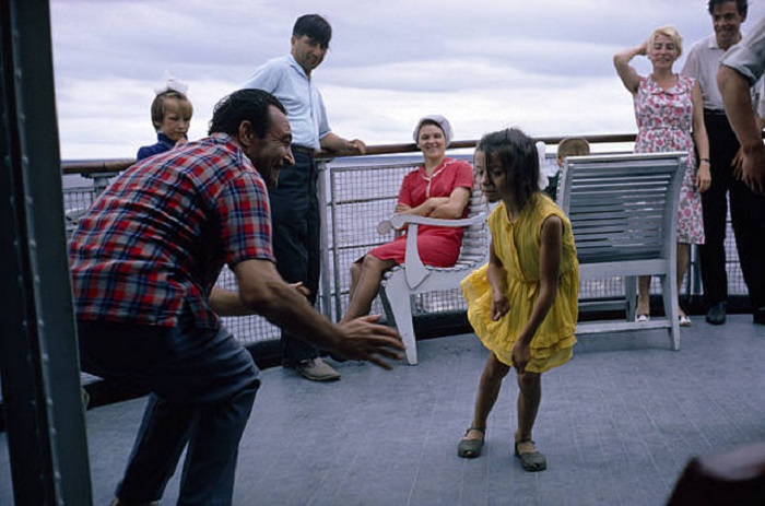На палубе теплохода один из гидов учит девочку танцевать твист.