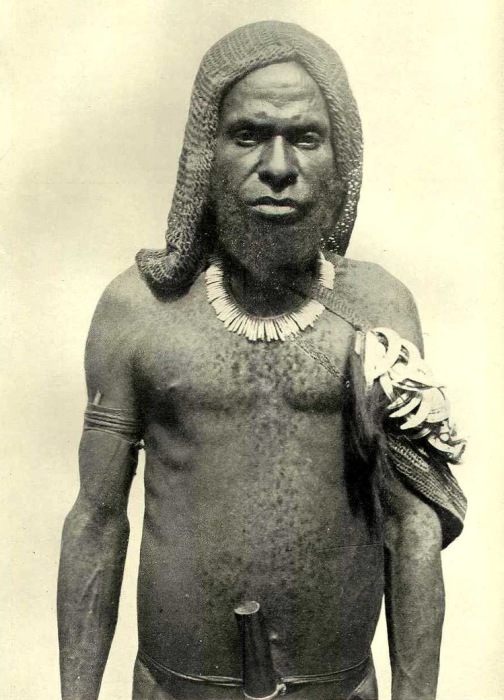 У туземца Гоелалое очень густая борода и много волос на теле, на левом плече - связка кабаньих клыков .