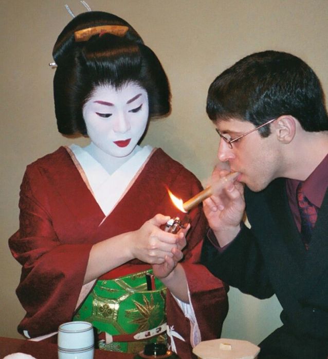Гейша подкуривает сигару иностранному гостю. | Фото: en.wikipedia.org.