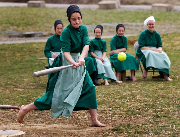 Девочка-подросток из семьи амишей играет в бейсбол.