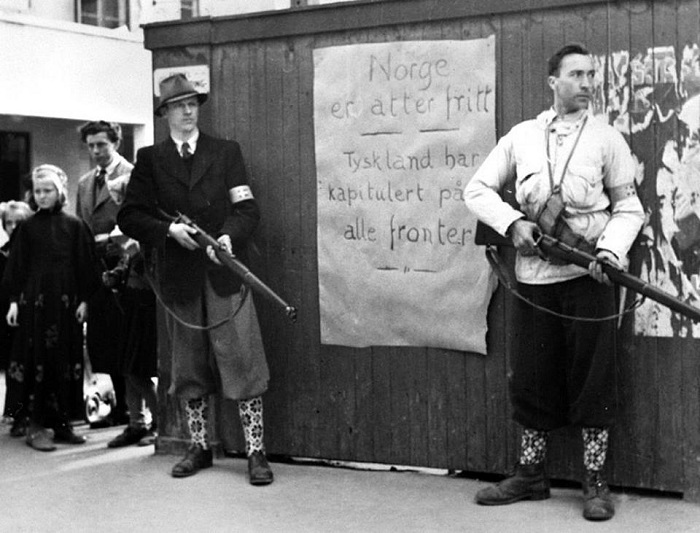 Участники норвежского сопротивления на фоне плаката «Норвегия снова свободна», город Берген.