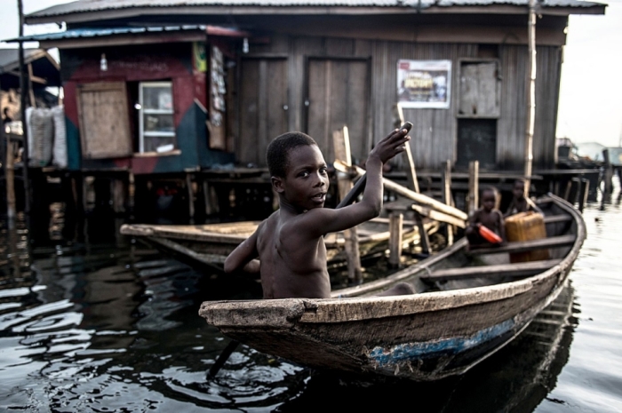 Мальчик плывет по  трущобам Макоко в Лагосе, которые прозвали «Африканской Венецией». Здесь живут тысячи горожан. /Фото: Мохаммед Эльшами
