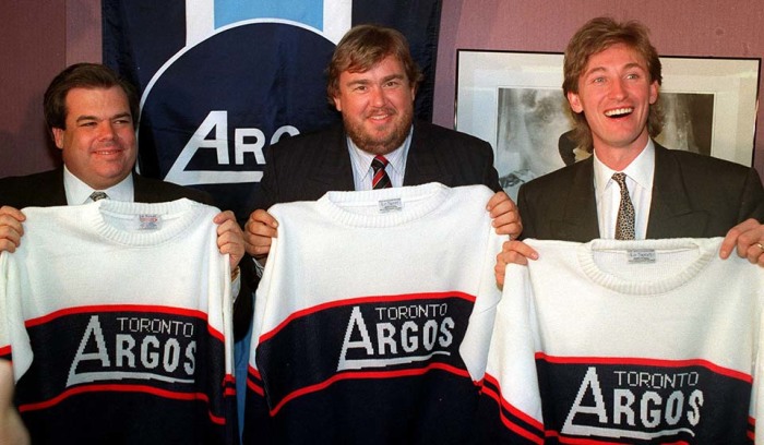 Брюс Макнолл, Джон Кэнди и Уэйн Гретцки демонстрируют свои новые майки «Торонто Аргонавтс» в феврале 1991 после того, как было объявлено, что они купили команду Канадской футбольной Лиги. / Фото: www.cponline.thecanadianpress.com