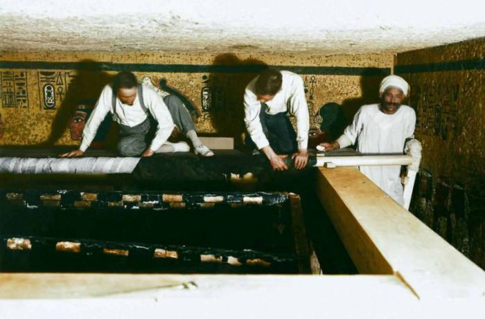 Картер и египетские рабочие сворачивают верхний покров с саркофага.