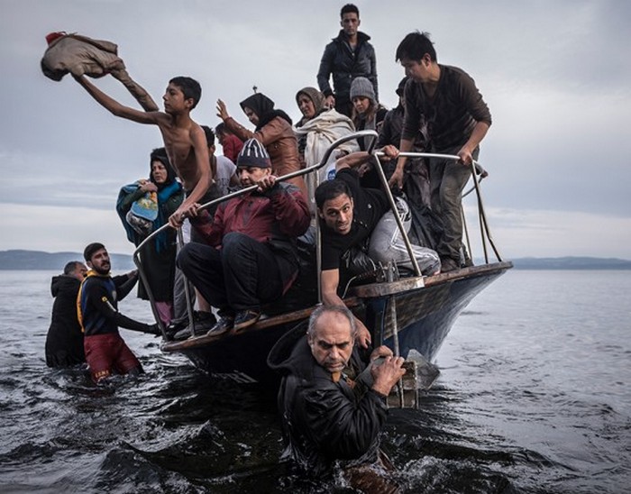 Турок на свой лодке высаживает беженцев недалеко от деревни Скала на греческом острове Лесбос. (The New York Times / Сергей Пономарев - 16 ноября 2015).
