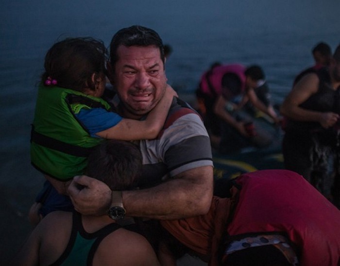 Плачущий житель Ирака Лаит Маджид с сыном и дочерью. Он до сих пор не может поверить, что семье удалось добраться до греческого острова Кос на хлипкой резиновой лодке. (The New York Times / Дэниел Эттер — 15 августа 2015)