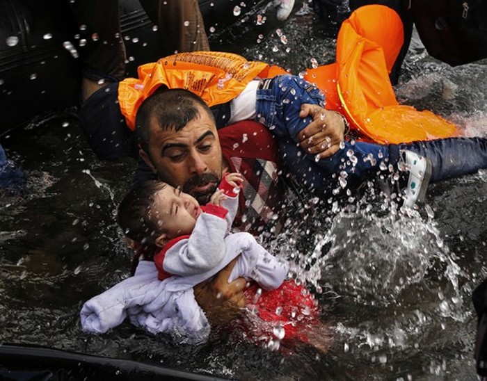 Сирийский беженец держит своих детей, чтобы те не выпали из лодки. Фото сделано возле острова Лесбос. (Thomson Reuters / Яннис Бехракис - 24 сентября 2015)